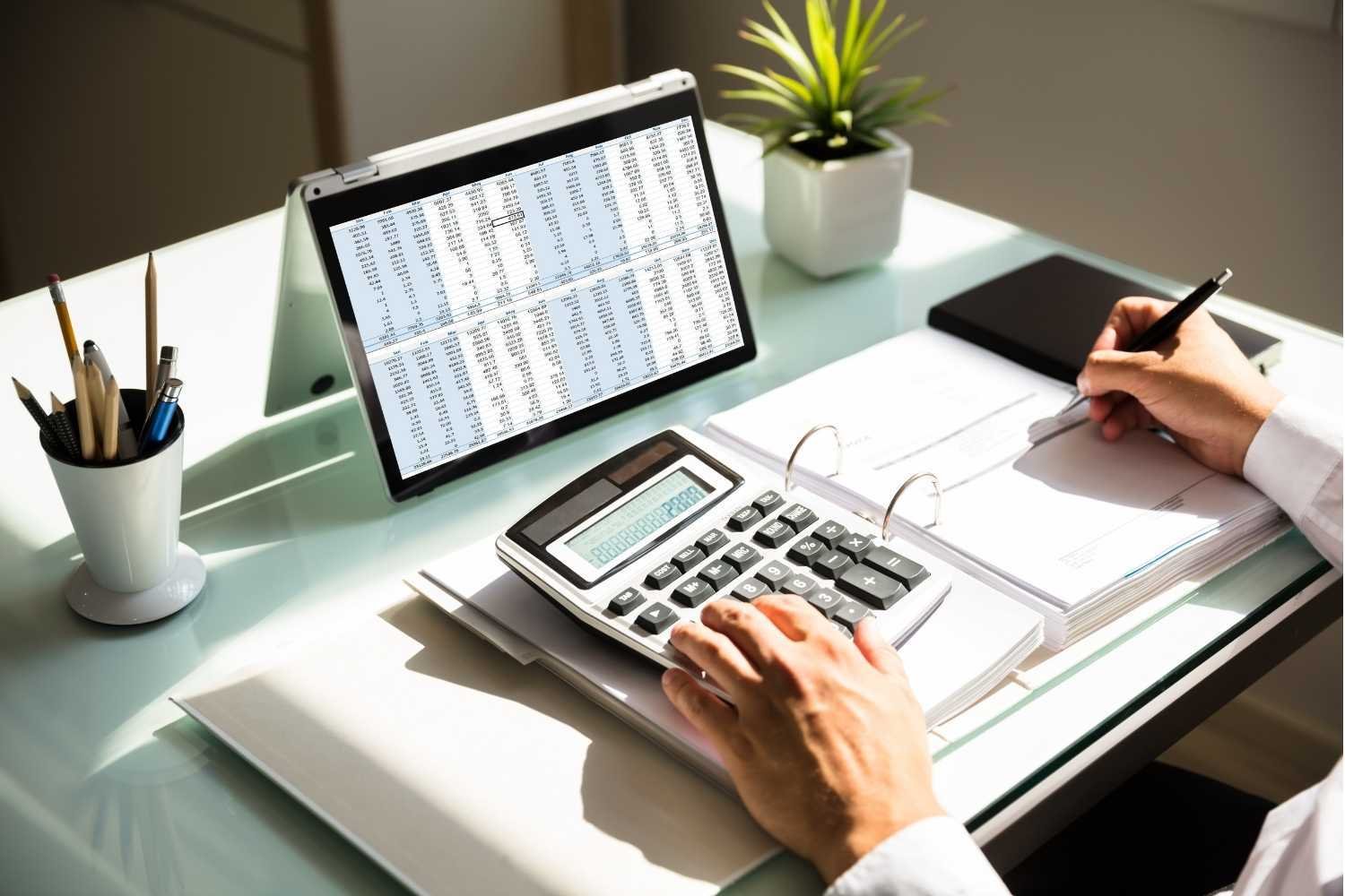 Accountant calculating company expenses with calculator and laptop
