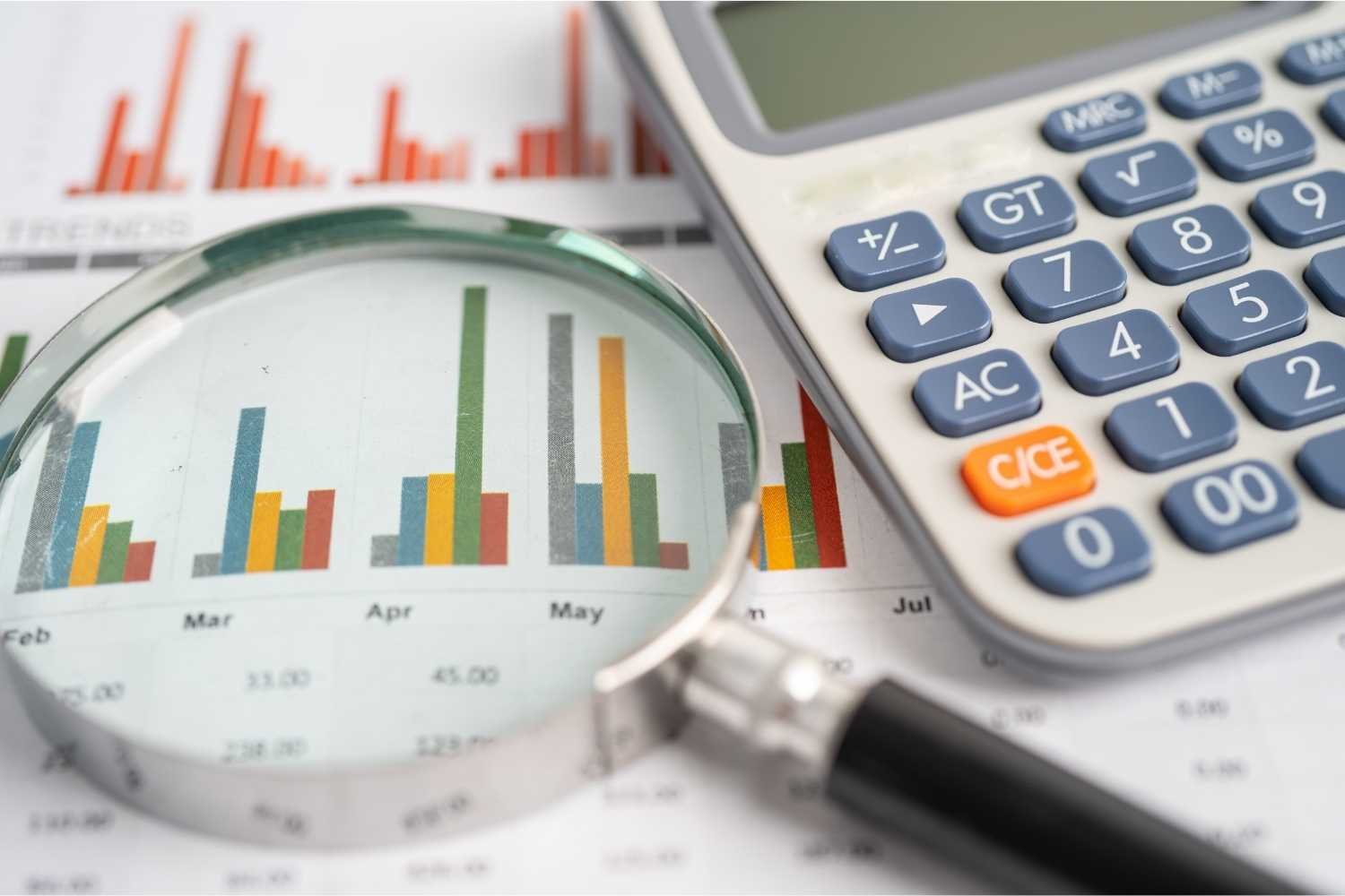 Magnifying Glass and Calculator on Charts Graphs Paper. Financia