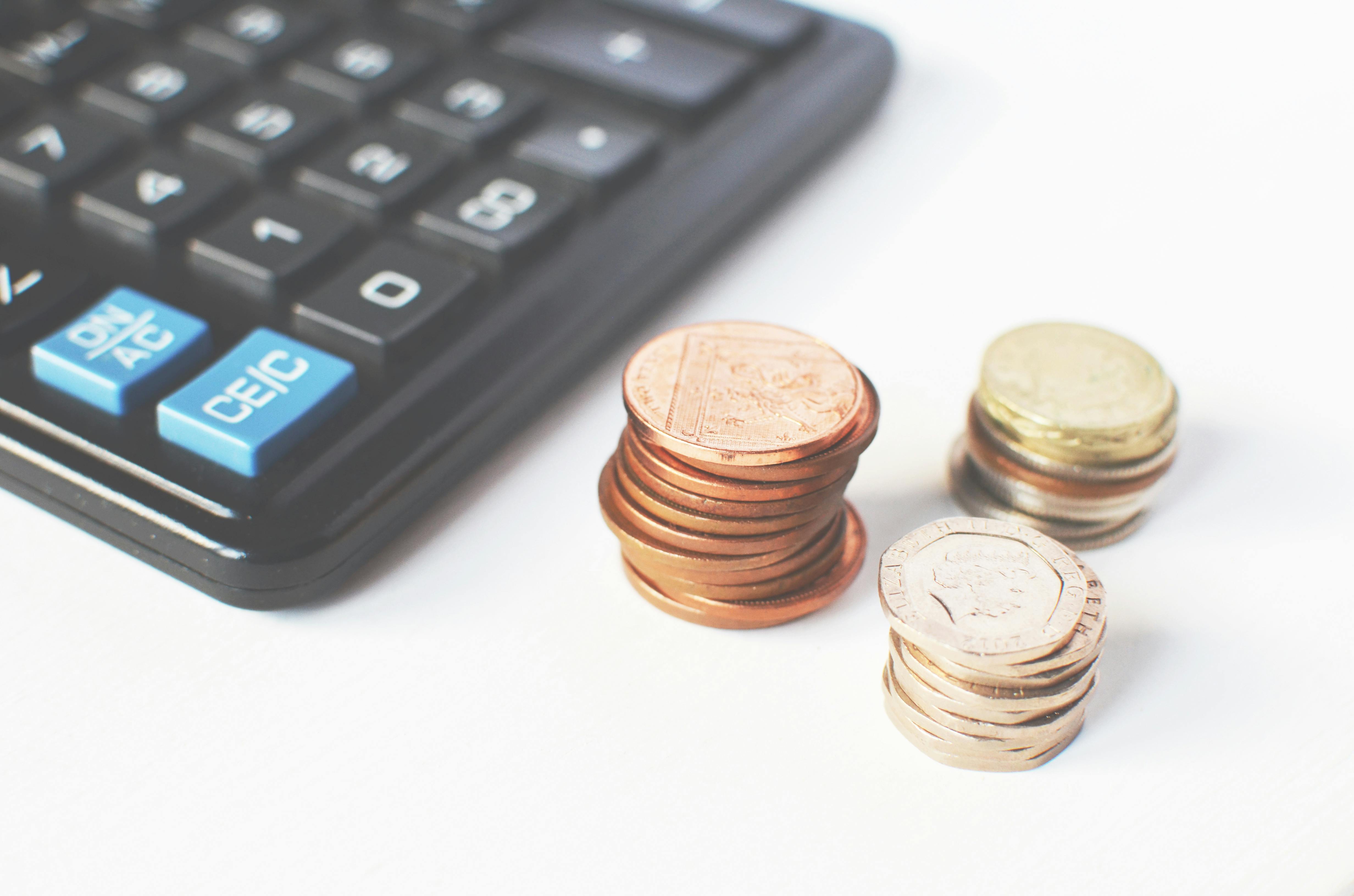 Stacks of coins beside a calculator representing cost calculation and budgeting