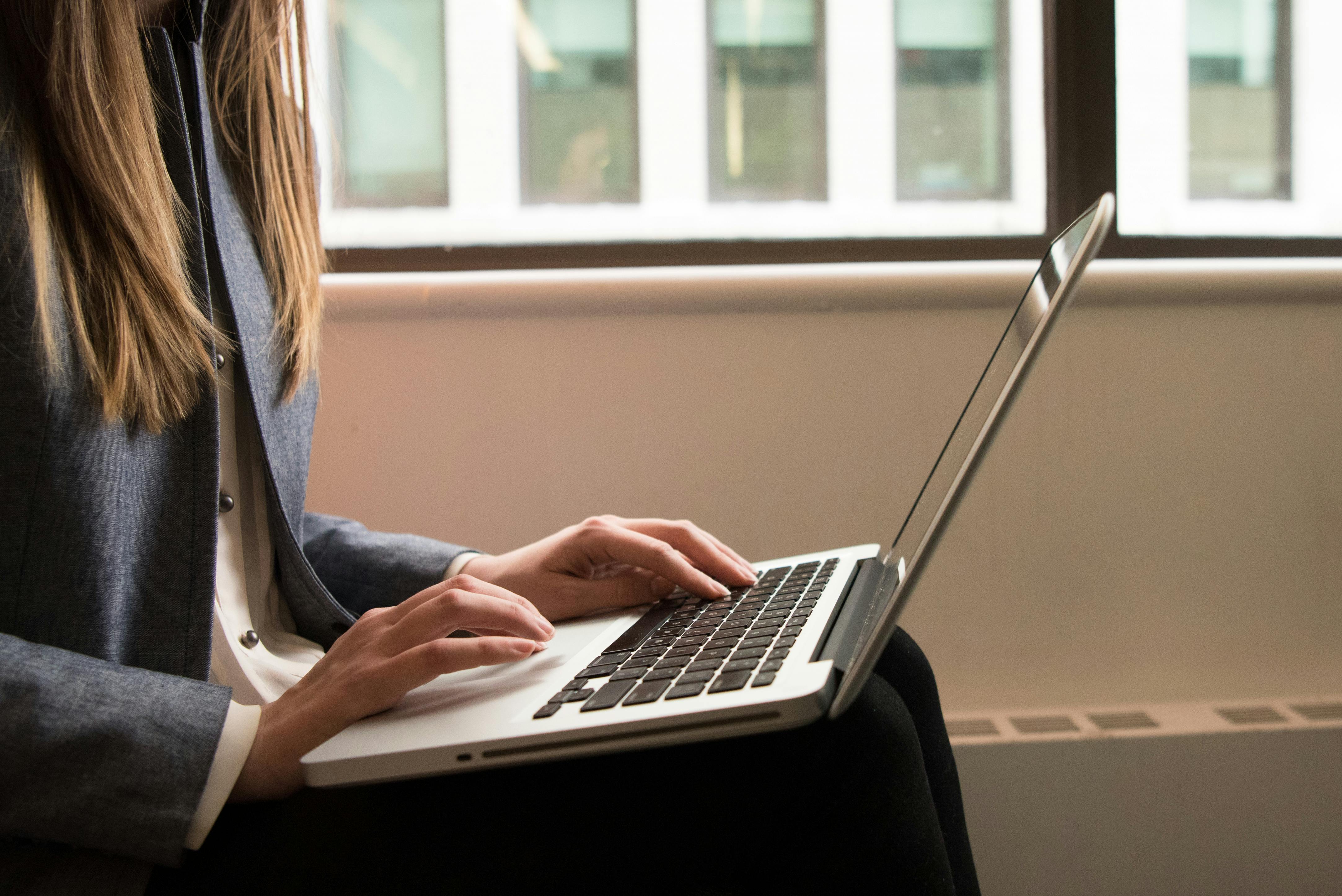 Businesswoman writing standard operating procedures on a laptop for an insurance agency.