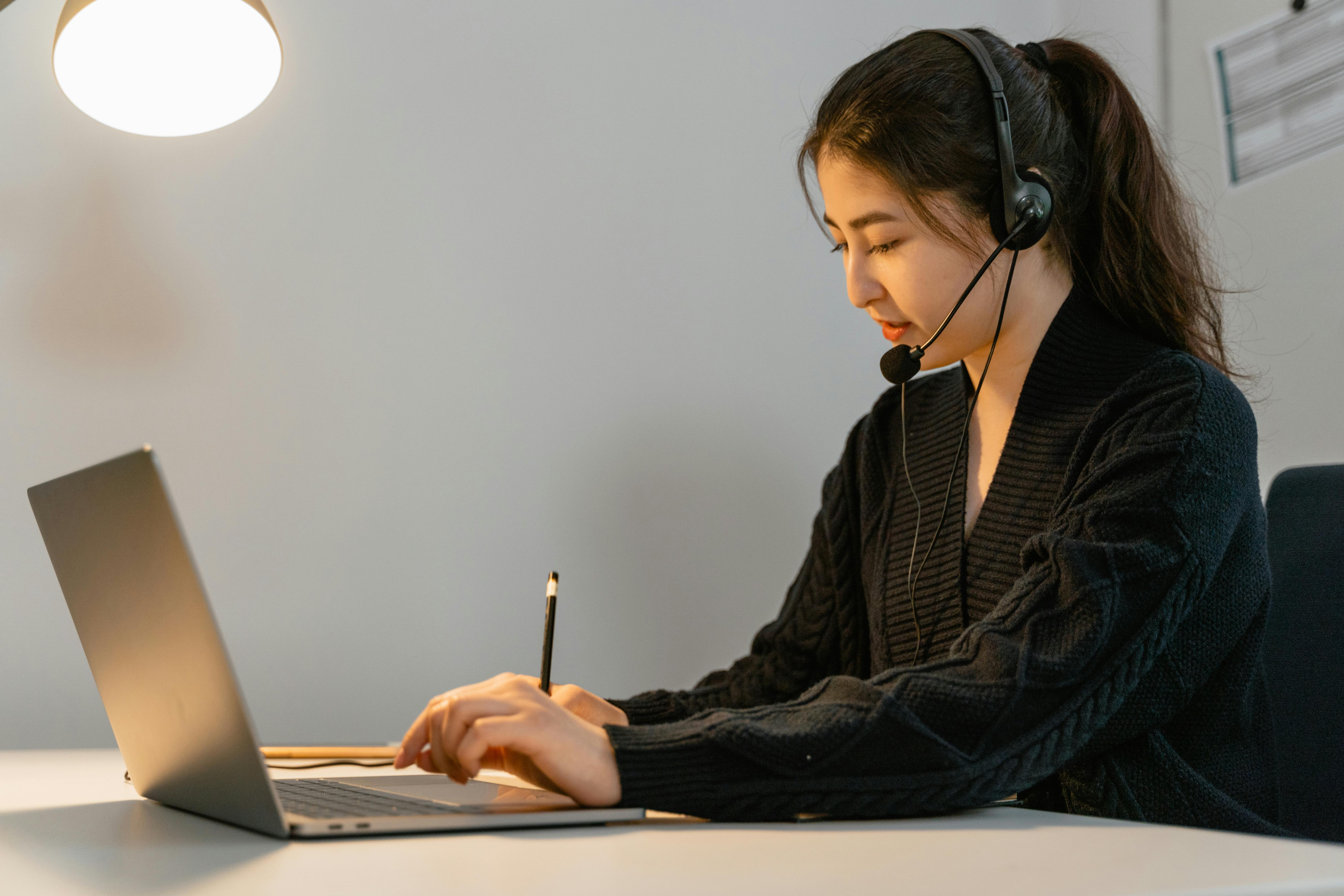 Virtual assistant working at a laptop while wearing a headset.