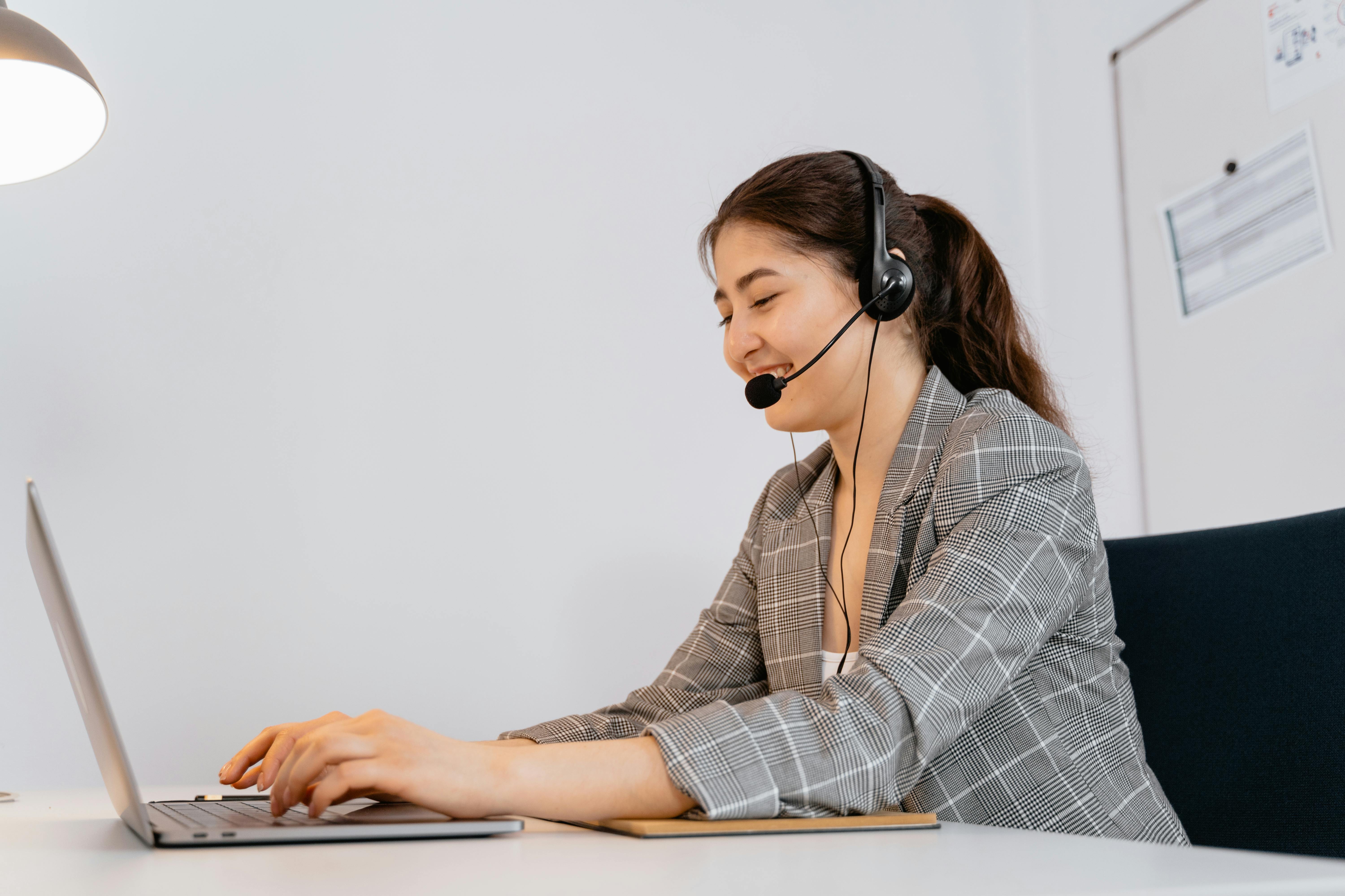 Insurance virtual assistant typing on laptop while speaking with a client through headset