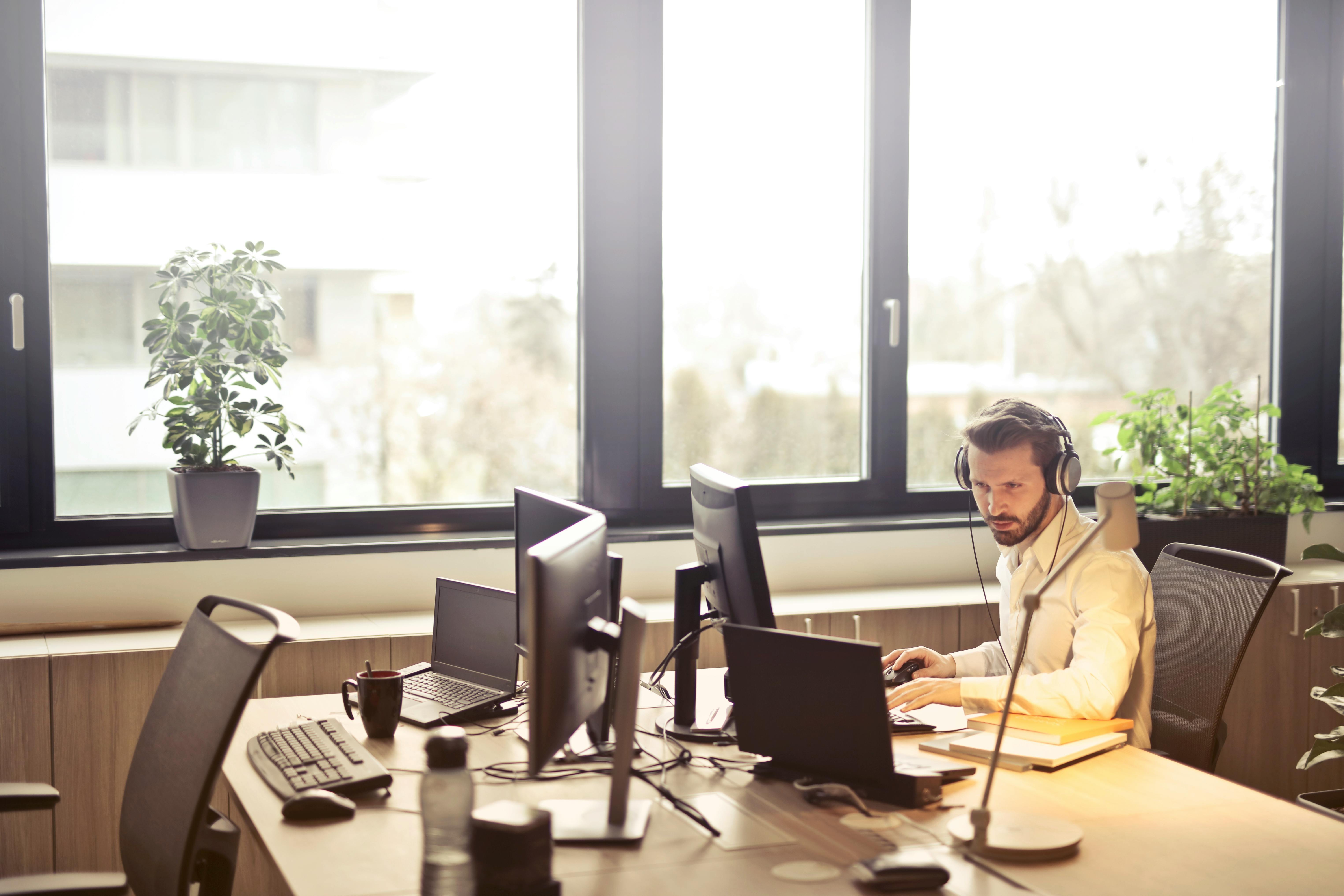 Professional working with multiple computer screens and headset in modern office