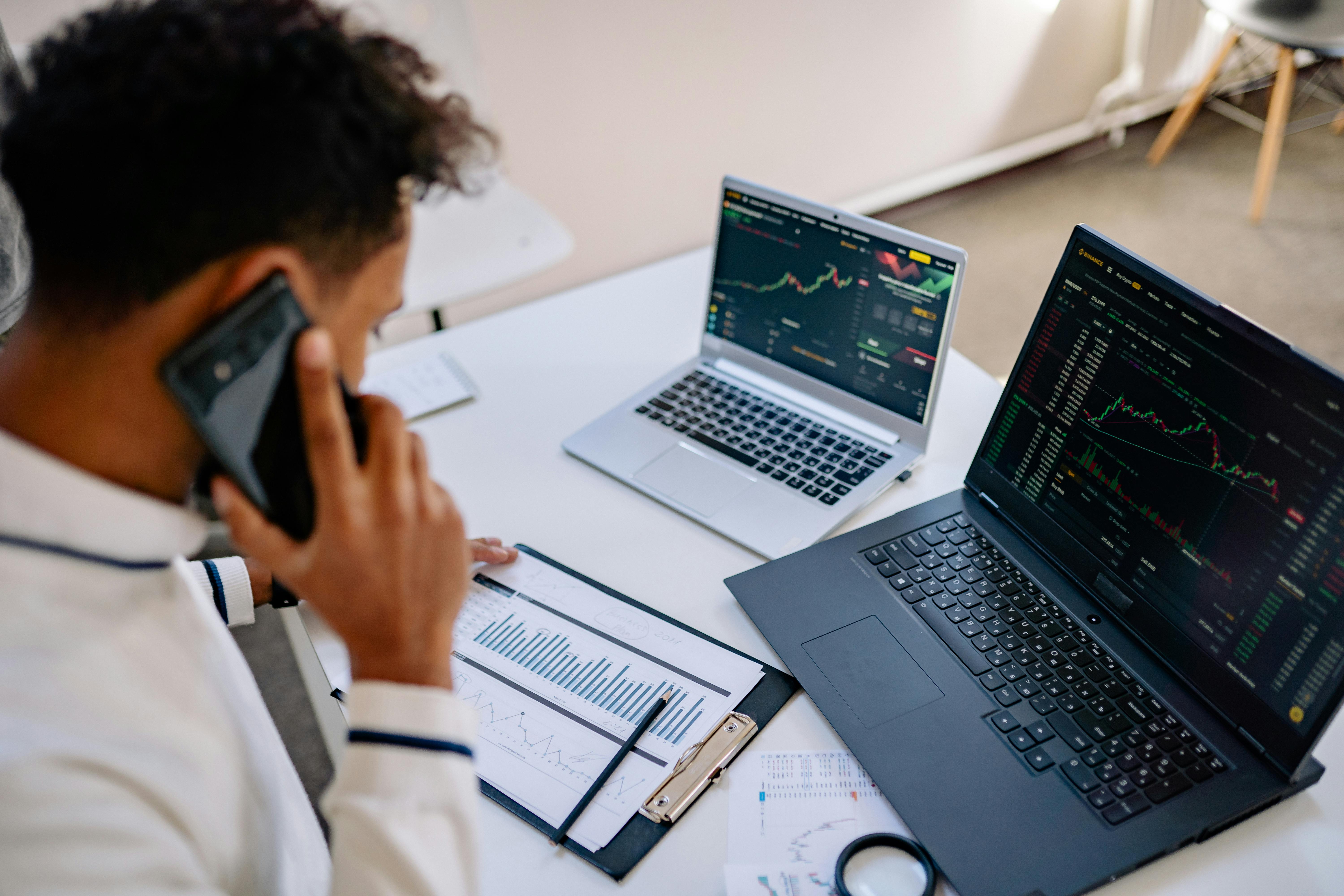 Professional reviewing analytics on laptops while discussing data over the phone