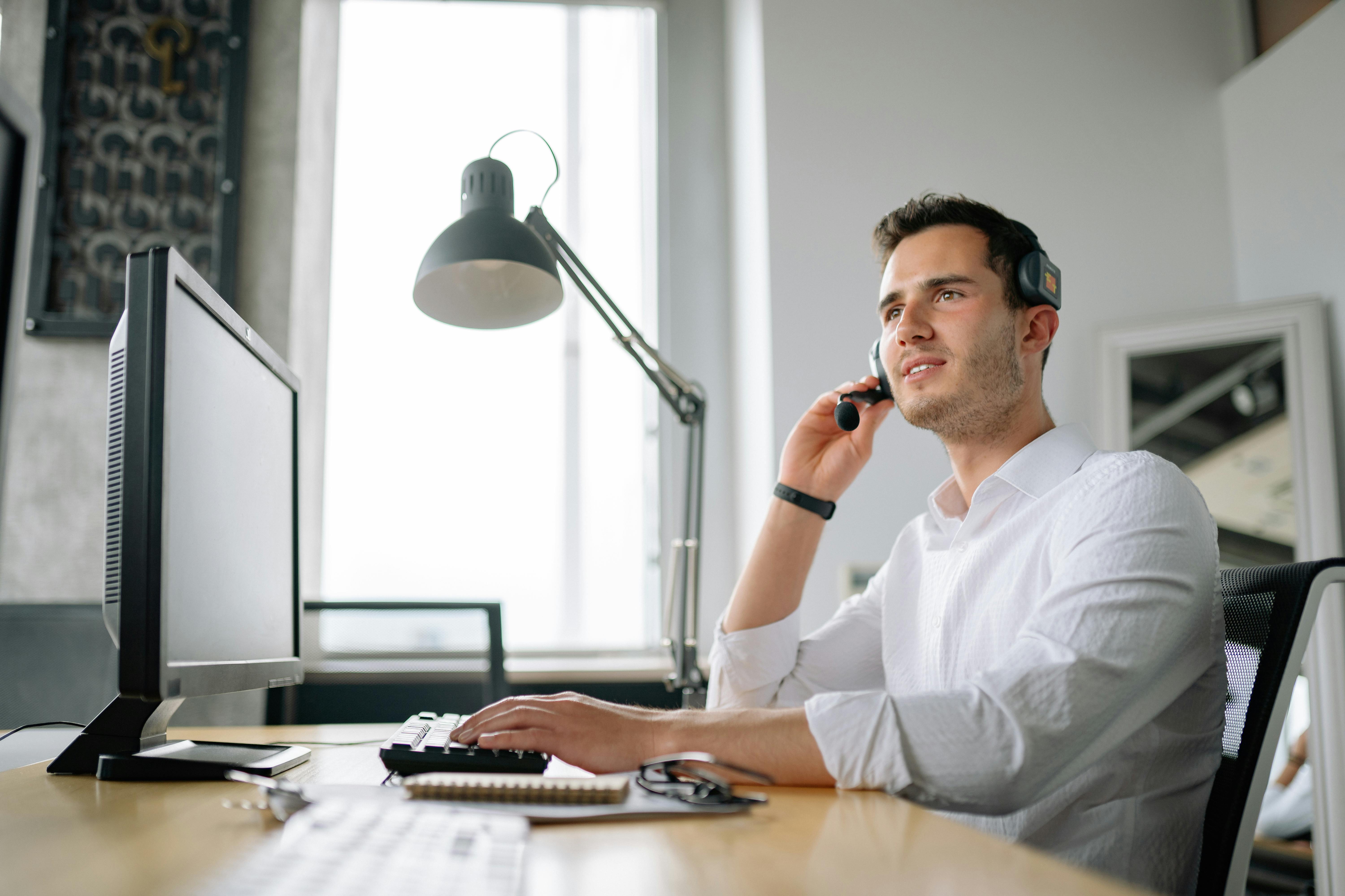 Office worker on a call with their insurance virtual assistant while working at a computer in a modern office